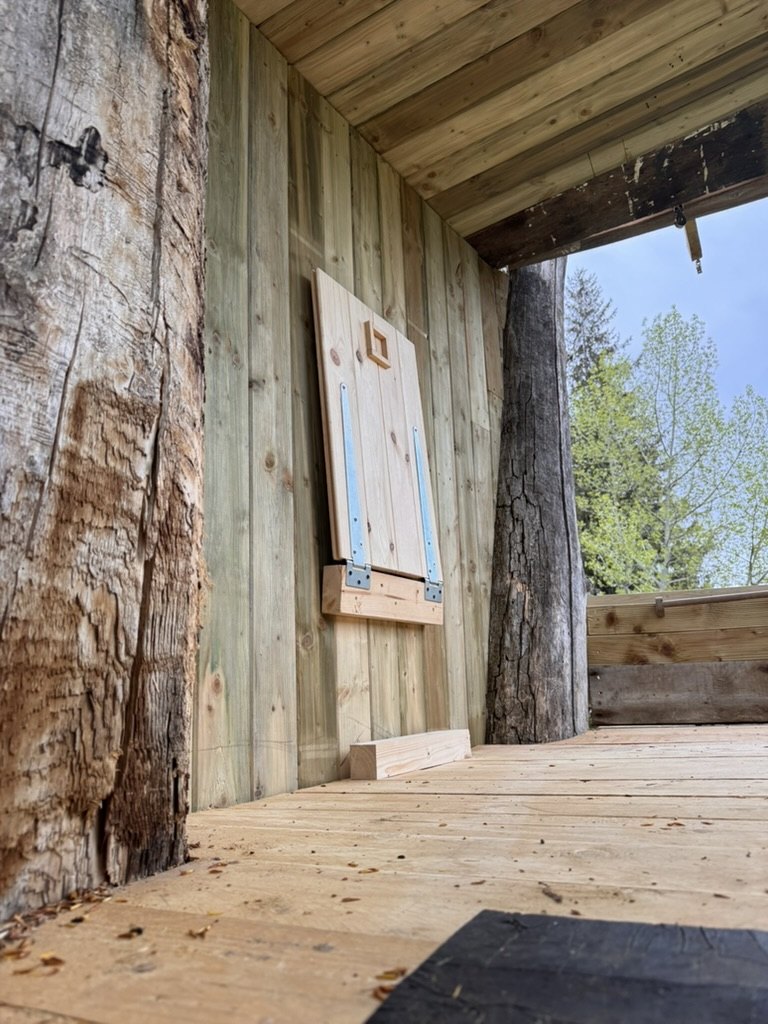 Fold-down wooden table hinged to a tongue-and-groove wall under a timber roof