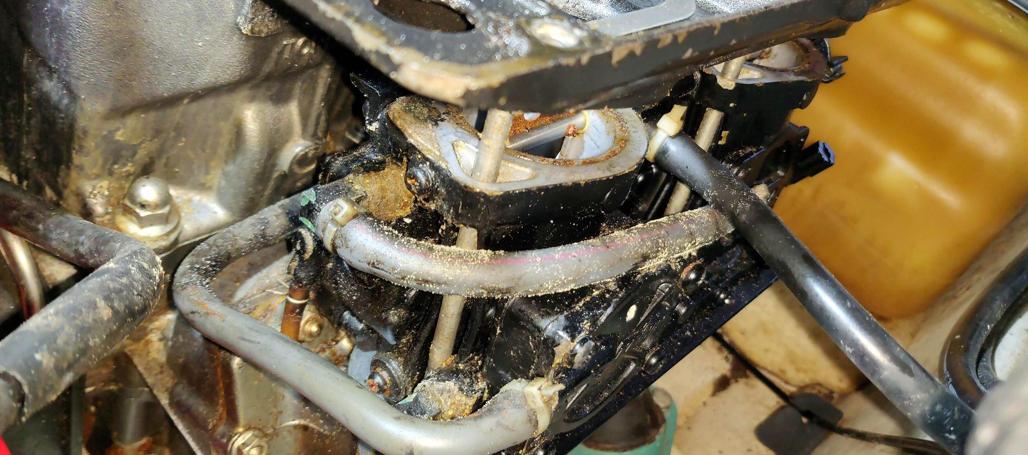 Close-up of carburetor and fuel lines in the engine bay
