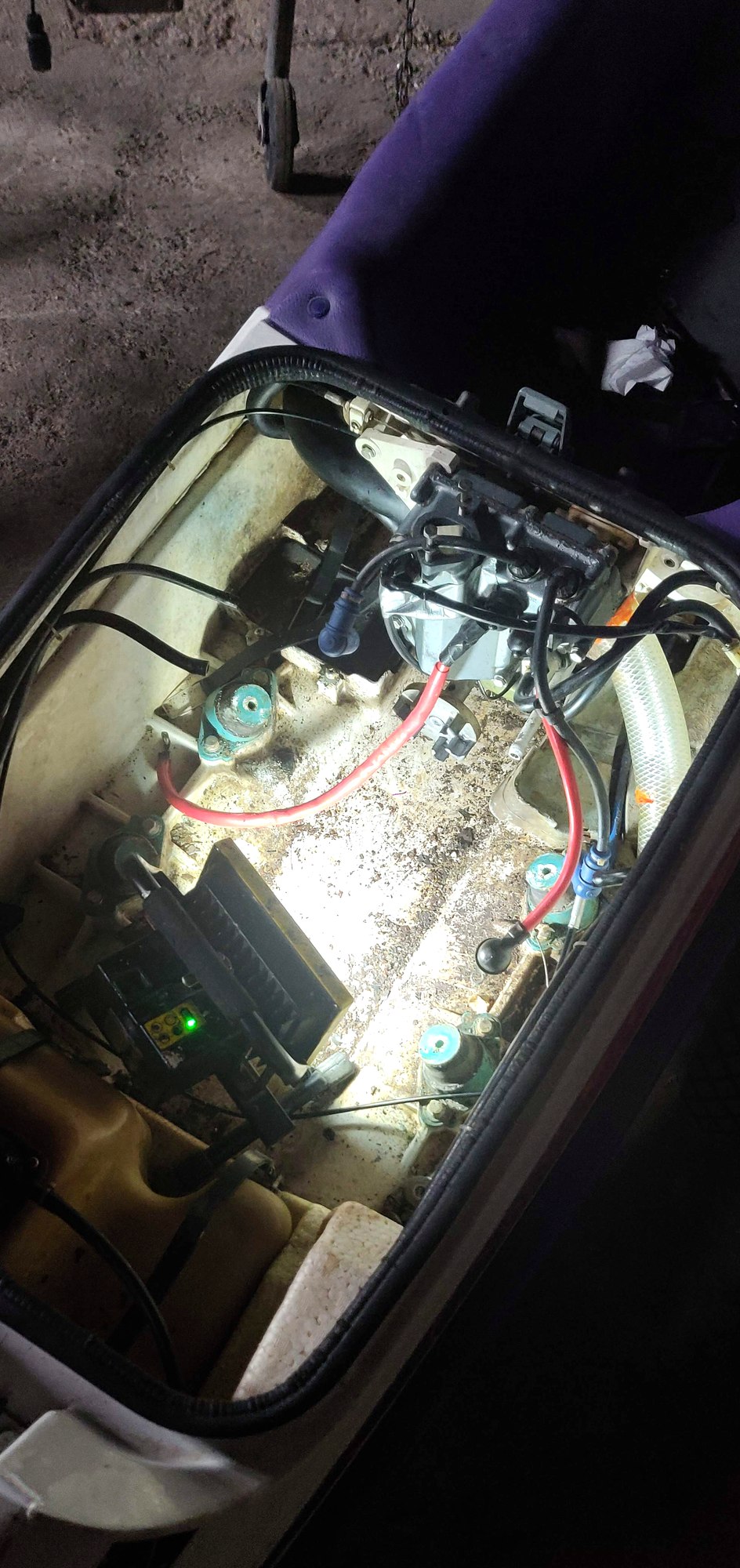Top-down view into the open engine bay lit by a work light