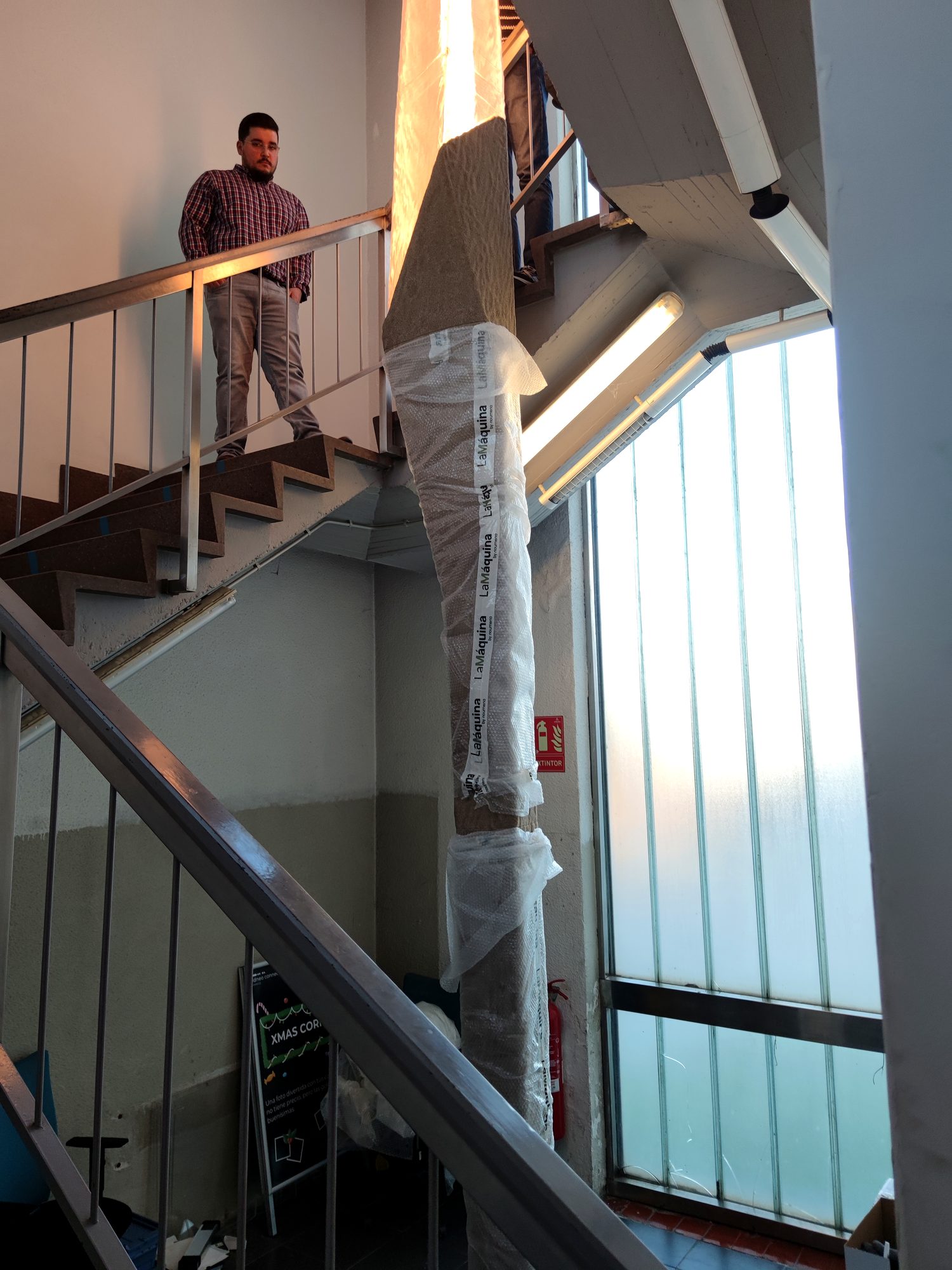 Tall wrapped prototype pillar standing in a concrete stairwell