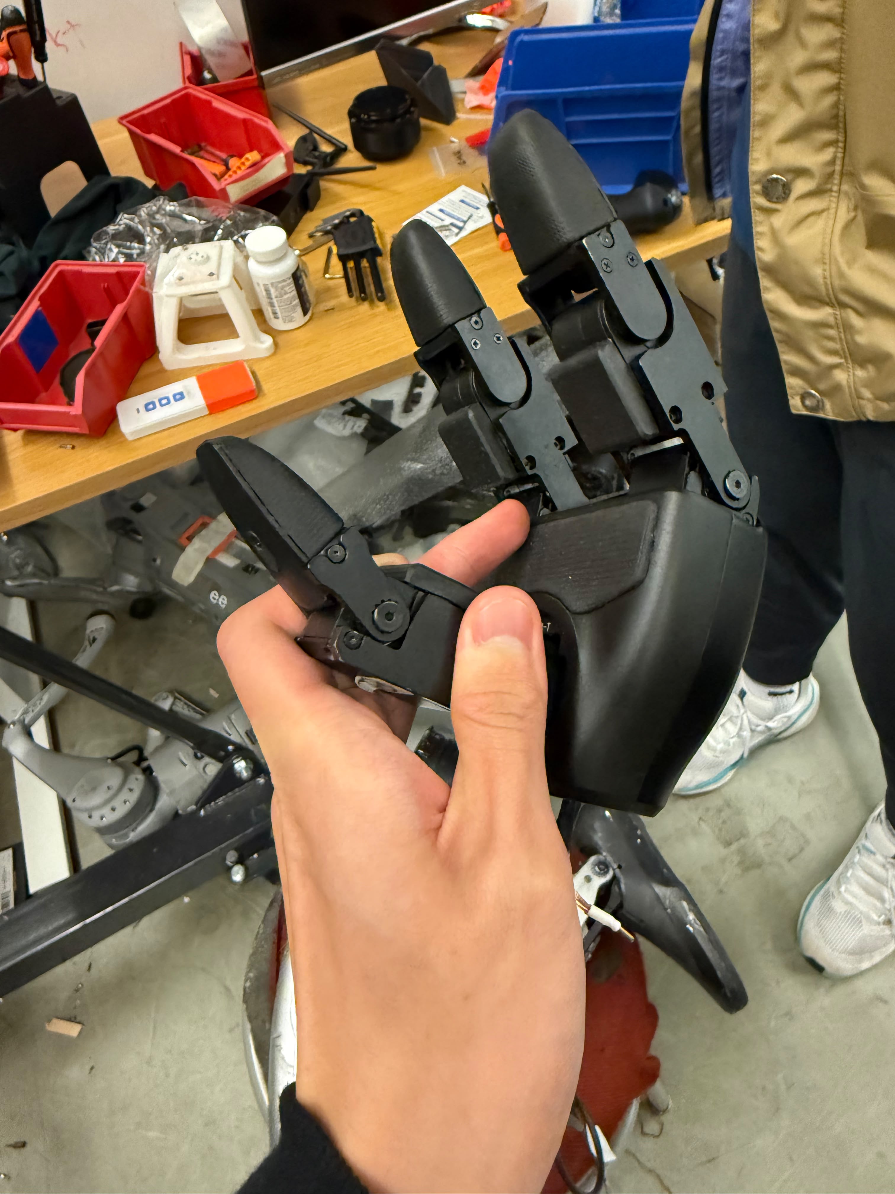 Three-fingered robotic gripper prototype held over a lab bench